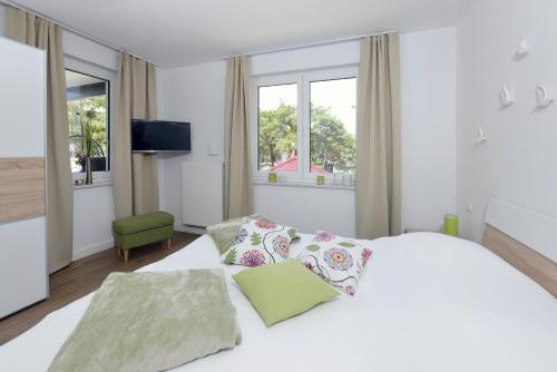 a white bedroom with a large bed and windows at Ferienwohnung Sonnensegler in Juliusruh