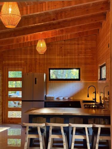 a kitchen with wooden walls and a refrigerator and stools at Casa Oregon Pucura in Traitraico