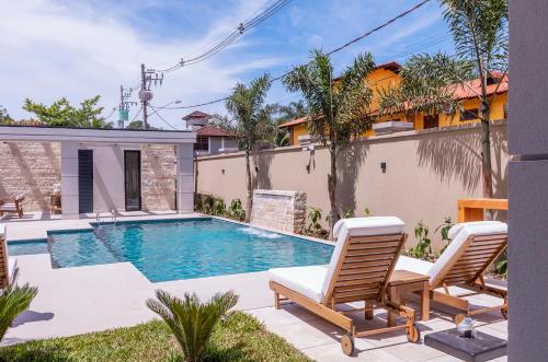 a backyard with a swimming pool and two chairs at Solena Hotel in Camburi