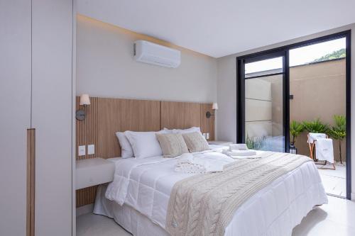 a bedroom with a large white bed with a large window at Solena in Camburi