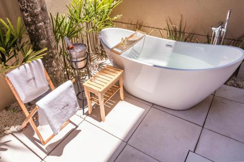 a white bath tub sitting on a patio with a chair at Solena in Camburi