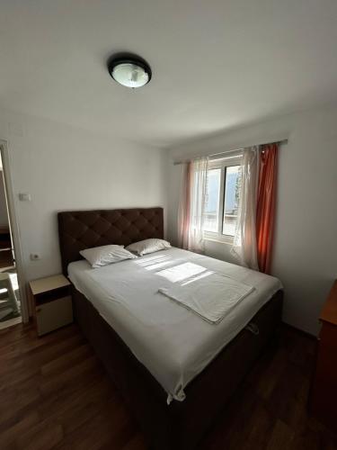 a bedroom with a bed with white sheets and a window at Apartmani Musić in Ulcinj