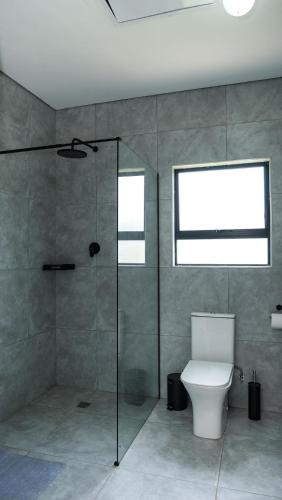a bathroom with a toilet and a glass shower at Mupauli Boutique Lodge in Hartbeesbult