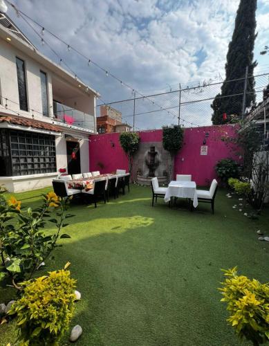 a yard with tables and chairs and a pink wall at Hotel Casa Ixtapan, Ixtapan de la Sal in Ixtapan de la Sal