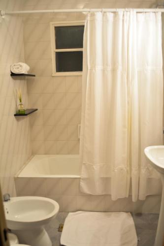a bathroom with a tub and a toilet and a sink at Argenta Apart Hotel in Trelew