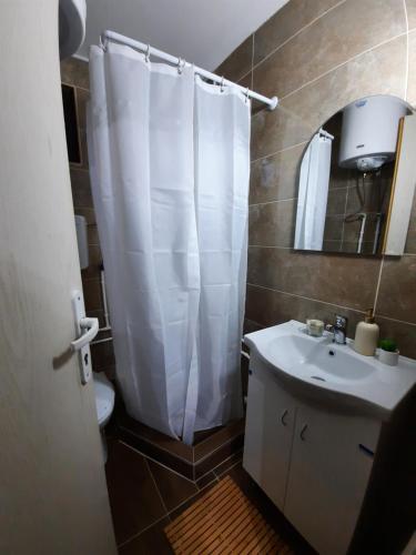 a bathroom with a white shower curtain and a sink at Vikendica Neven 3 in Popovići
