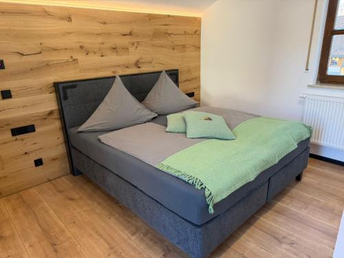 a bed in a room with a wooden wall at woidpanorama 3 Appartement in Neuschönau