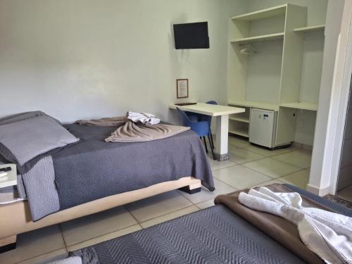 a bedroom with a bed and a desk and a table at Hotel Pousada Marra in Catalão