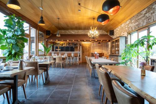un ristorante con soffitti in legno, tavoli e sedie di B&B De Leestjespolder a Moerkerke