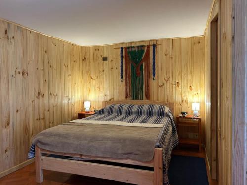 - une chambre avec des murs en bois et un lit avec deux lampes dans l'établissement Hostal Aves del Sur Coñaripe, à Panguipulli