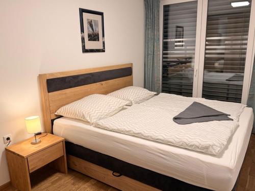 a bed in a bedroom with a lamp and a window at Alpenblick 2 in Größing