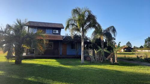 una casa con palme di fronte a un cortile di Cabana Raio de Sol RS a Osório