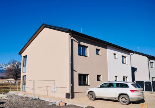 une maison blanche avec une voiture garée devant elle dans l'établissement Apartman SKY Tatry, à Veľký Slavkov