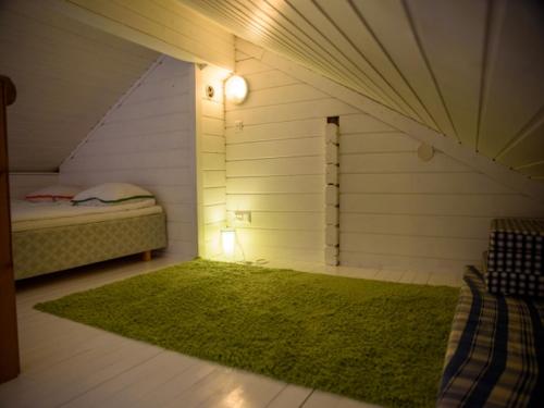 a small attic room with a bed and a green rug at Sappee Peak Cabin - Bike, Fire, Snow & Adventure in Salmentaka