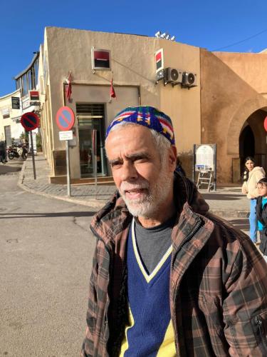 een man met een bandana staat op straat bij Riad Dar Lemdrssa in Fès