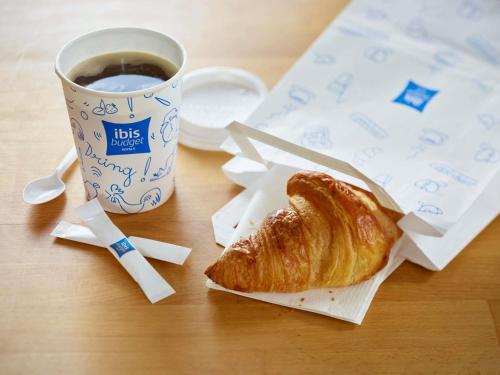 a table with a cup of coffee and a croissant at ibis budget Bergerac in Bergerac