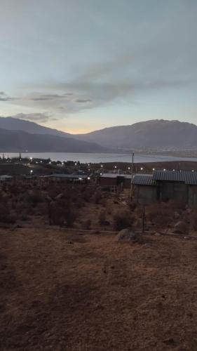 een uitzicht op een veld met een gebouw en het water bij La Apacheta in Tafí del Valle