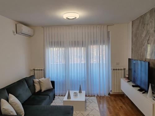 een woonkamer met een blauwe bank en een televisie bij Royal Queen in Vrnjačka Banja