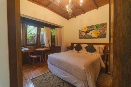 a bedroom with a bed and a table and a window at Pousada Tucano Do Cuiabá in Itaipava