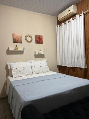 a bedroom with a bed with a blue blanket and a window at Quarto em Casa familiar in Belém