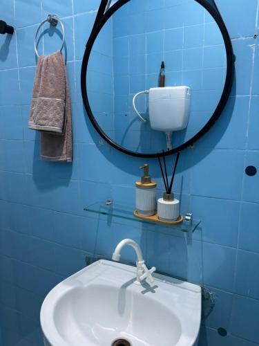 a blue bathroom with a sink and a mirror at Quarto em Casa familiar in Belém