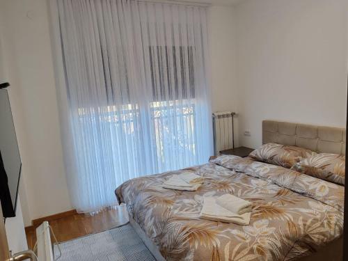 een bed in een slaapkamer met een groot raam bij Royal Queen in Vrnjačka Banja