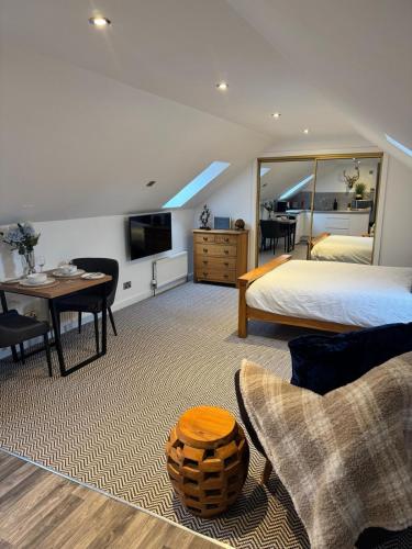 ein Schlafzimmer mit einem Bett, einem Tisch und einem Fernseher in der Unterkunft An Cuiltheann Apartment in Turriff