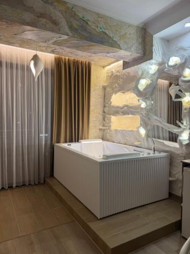 een badkuip in een badkamer met een stenen muur bij Ilio Boutique Hotel in Ksamil