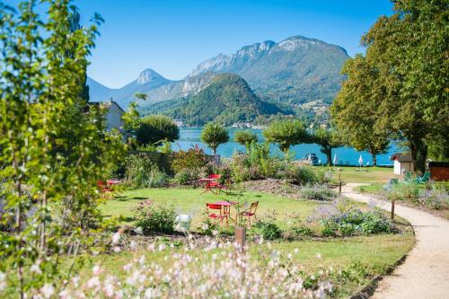 a garden with a lake and mountains in the background at Hôtel Beau Site Talloires B SPA in Talloires