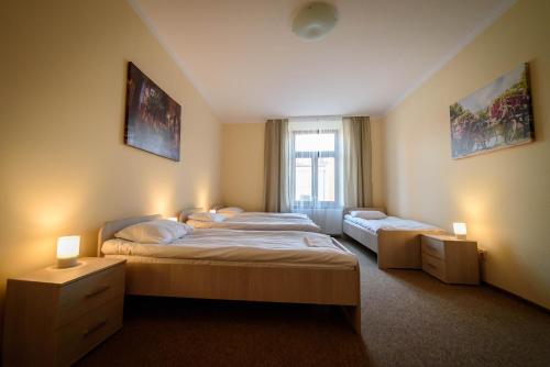 two beds in a room with two lamps and a window at Apartamenty Wałowa 4 in Tarnów