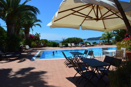 a pool with tables and chairs and an umbrella at Residence Fenicia in Villasimius