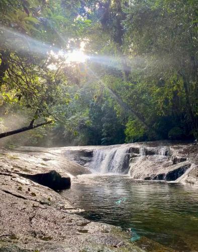 a waterfall in the middle of a river with the sun shining at Hogar na mata in Ubatuba