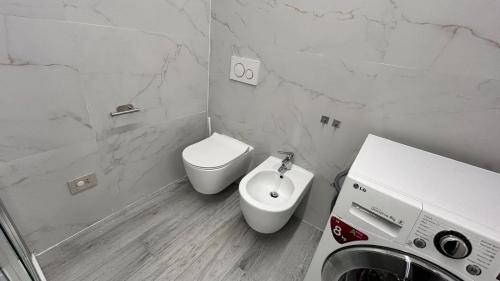 a white bathroom with a toilet and a sink at Baratà Apartments 2 in Savigliano