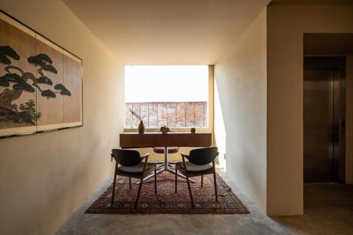 a table and chairs in a room with a window at Hotel Oculto in Mexico City