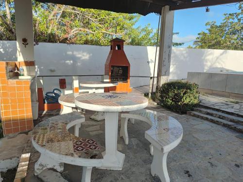 eine Terrasse mit einem Tisch, 2 Stühlen und einem Kamin in der Unterkunft Casa de Fagundes PB in Lucena