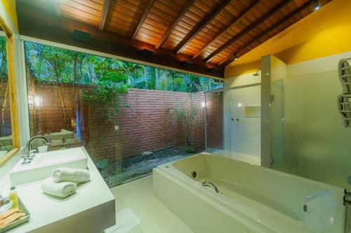 a bathroom with a tub and a sink and a window at Pousada Tucano Do Cuiabá in Itaipava