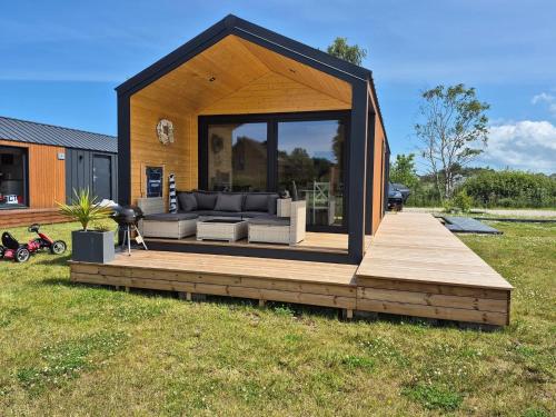een klein huisje met een bank op een houten terras bij Zakątek Dębki in Dębki