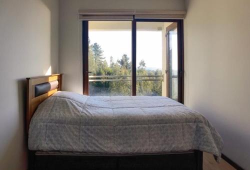 een slaapkamer met een bed en een groot raam bij Casa Pingueral Tomé in Concepción