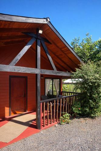 eine rote Scheune mit Veranda und Tür in der Unterkunft Cabañas los Jardines de Lican ray in Licán Ray
