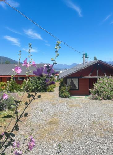 une maison avec des fleurs violettes devant dans l'établissement Cabañas los Jardines de Lican ray, à Licán Ray