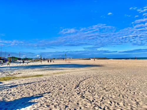 a beach with people walking on the sand at Sol Calor e Mar, achei minha pousada in Matinhos