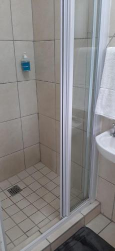 a shower with a glass door in a bathroom at Grace Villas 30 in East London
