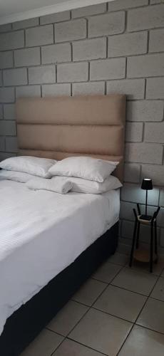 a bed with white pillows and a brick wall at Grace Villas 30 in East London