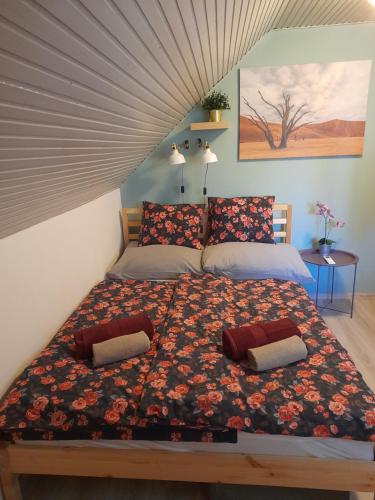 a bedroom with a large bed with a floral comforter at Nárcisz Vendégház 2 in Mezőkövesd