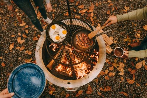 a group of people cooking food over a fire at Postcard Cabins Machimoodus, Outdoor Collection by Marriott Bonvoy in Moodus