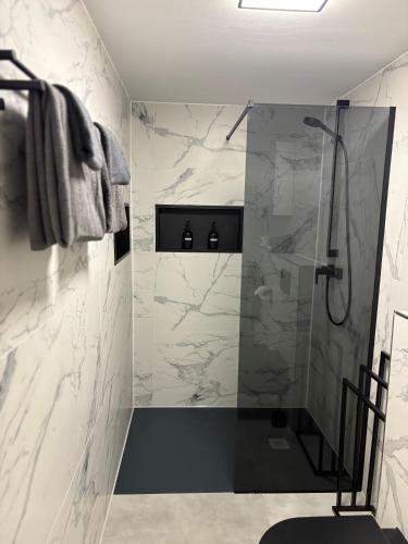 a bathroom with a shower with marble walls at Ferienwohnung Relax - mit Whirlpool & Sauna in Medebach