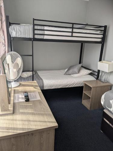 a dorm room with two bunk beds and a desk at Corner House Hotel Gatwick with bookable Holiday parking in Horley