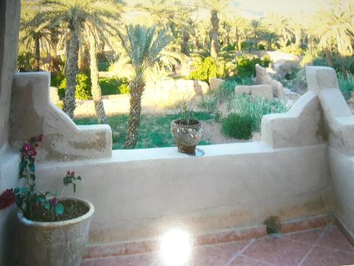 een wit bad met palmbomen op de achtergrond bij La maison de palmeraie in Tamnougalt