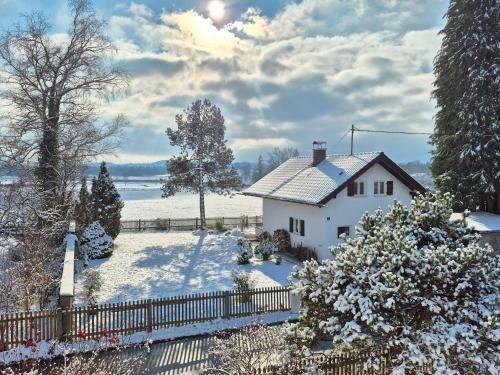 a white house in the snow with a fence at The Staffelsee Lodge in Uffing