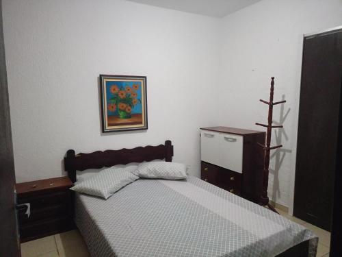 a bedroom with a bed and a picture on the wall at Moinho dos ventos in São Pedro da Aldeia